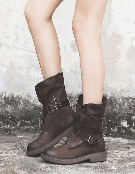 Brown leather boots worn by a person on a textured surface with a neutral background