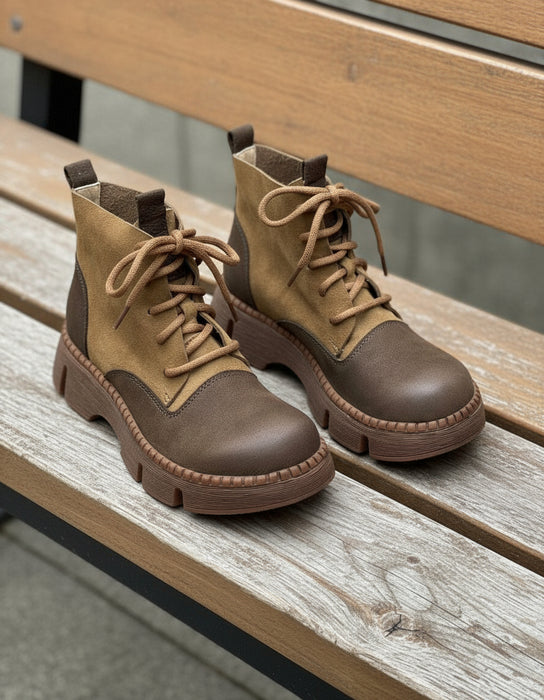 Pair of brown leather boots with laces on a light gray background