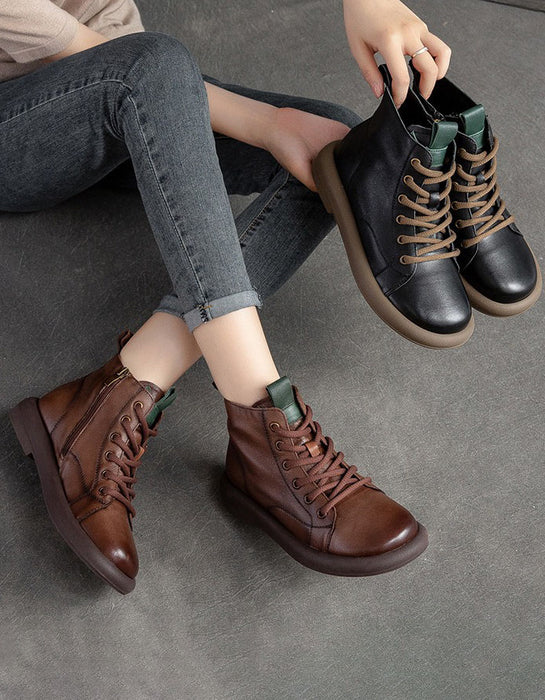Person wearing brown leather boots on a gray floor, holding black boots.
