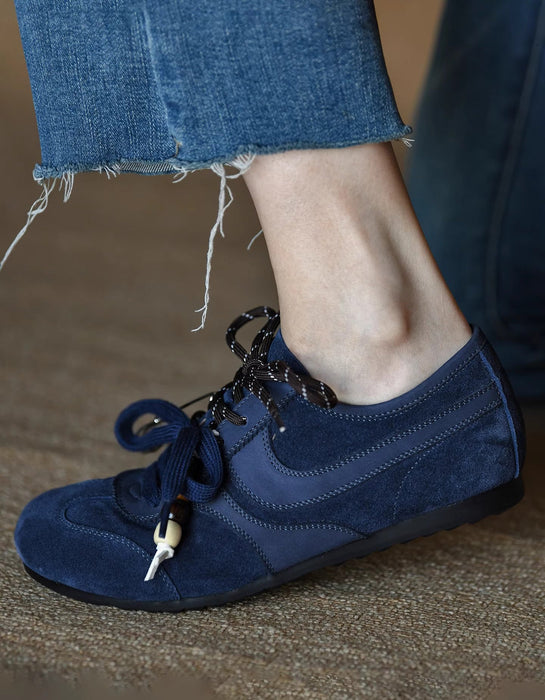 Blue suede shoe with a decorative tag worn by a person in jeans.