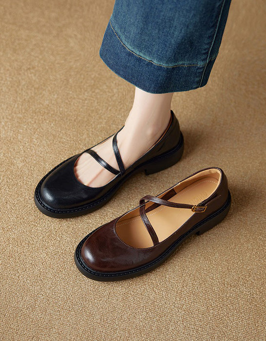 Pair of black and brown flat shoes on a beige surface