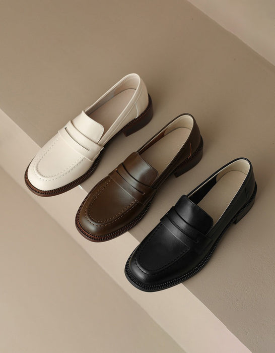 Three loafer shoes in white, brown, and black on a beige background
