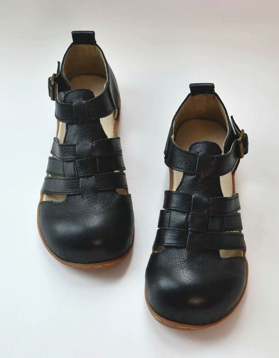 A pair of black leather wide toe box sandals with cutout straps and adjustable buckle straps