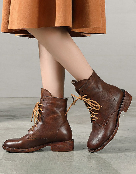 Brown leather boots worn with a matching skirt on a gray background