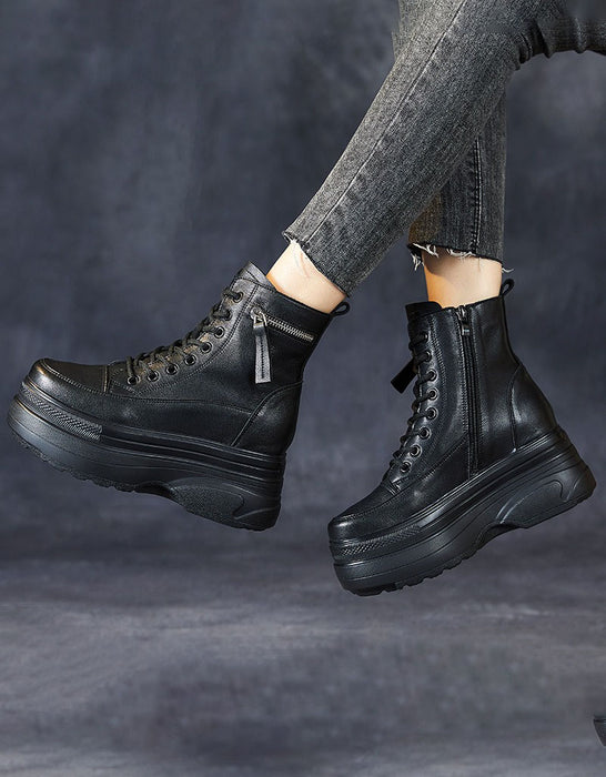 Black leather boots worn with gray pants on a dark background